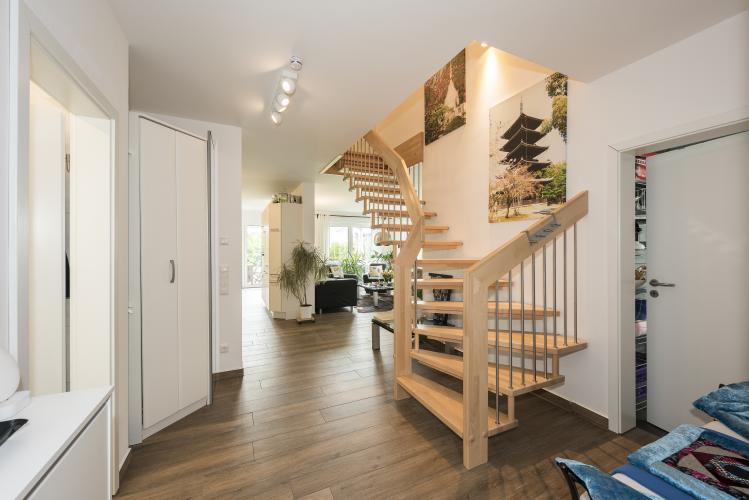 Stilvoll und nachhaltig – die viertelgewendete Treppe zum Obergeschoss ist in Holz aus zertifiziert nachhaltiger Waldwirtschaft gefertigt.<i> Foto: Roth-Massivhaus / Gerhard Zwickert</i>